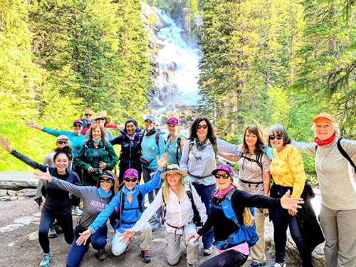 A group of women posing in front of a waterfall on the Women's Quest Jackson Hole retreat