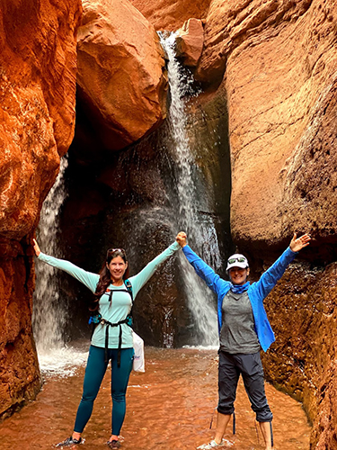 Two women posing under a waterfall during the Women's Quest Canyonlands retreat