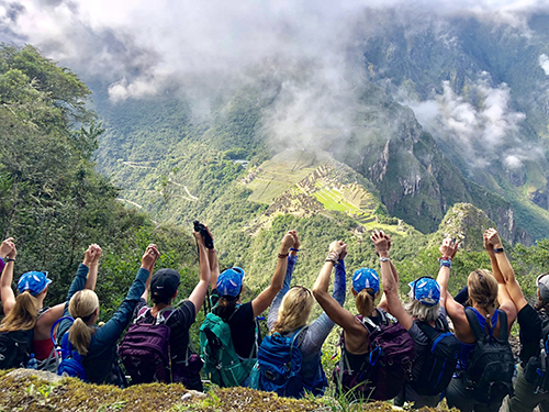 Women holding their hands up in excitement during a hike in Peru