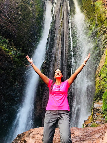 Woman with her hands outstretched under a waterfall in Peru