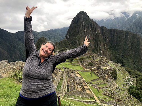Woman with her hands up with Machu Picchu in the background. 