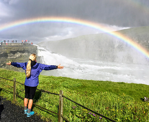 Colleen Cannon posing with a rainbow in Iceland