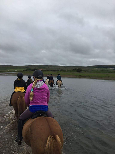 Horseback riding through water on our Iceland retreat