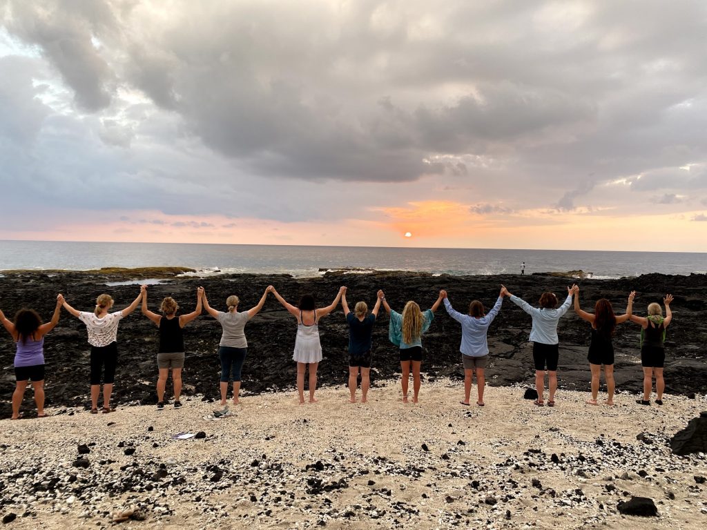Women Questers with their arms up on a beach in Hawaii